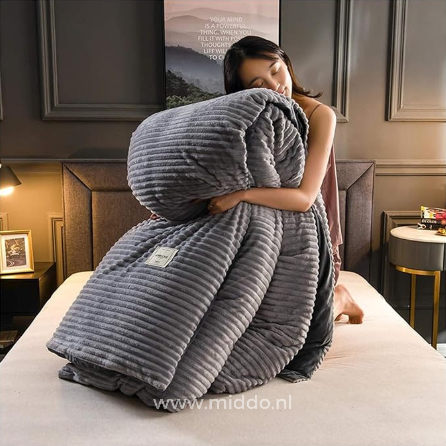 Vrouw met opgevouwen grijs dekbedovertrek met dekbed erin  op een bed