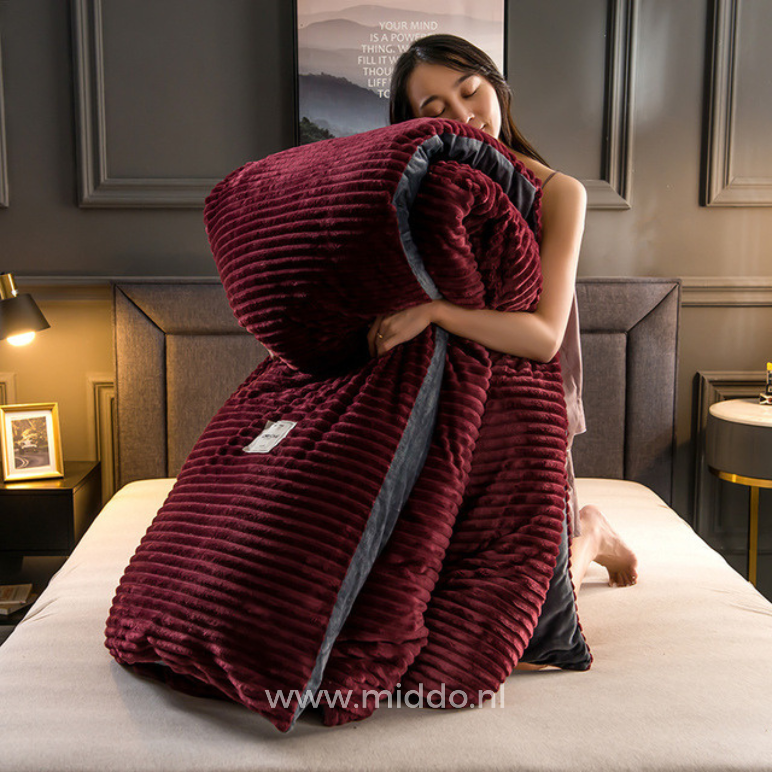 Vrouw met opgevouwen wijnrood dekbedovertrek met dekbed erin op een bed