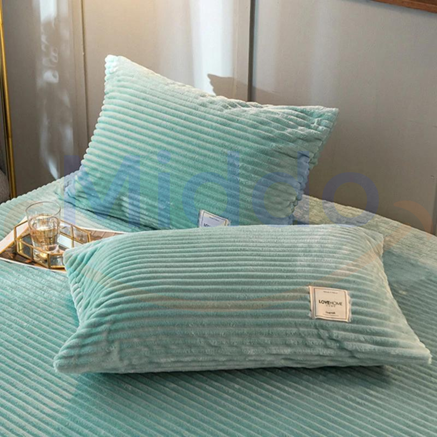 Jadegroene fluwelen fleece kussens op bed met glazen decoratie.