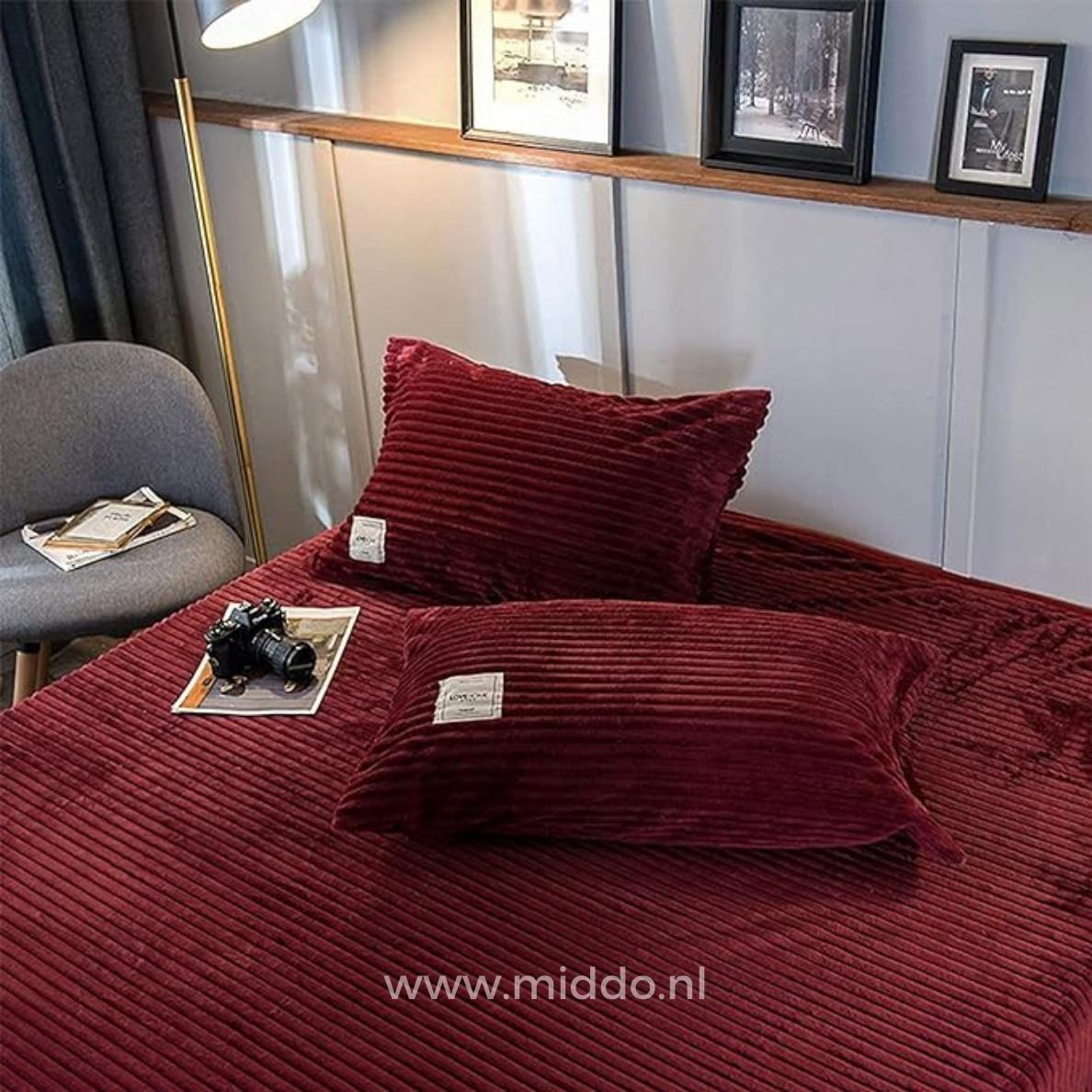 2 kussens met wijnrode kussenslopen op een bed
