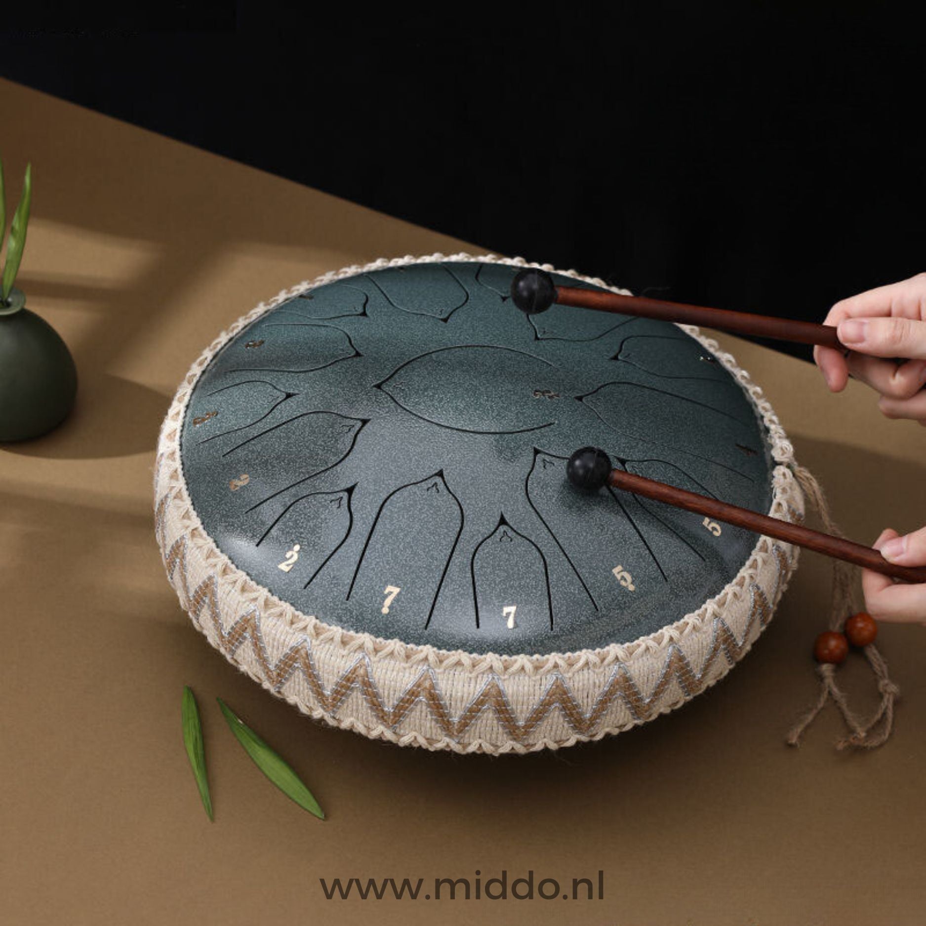 Handen bespelen een jade Harmonii KlankOase Steel Tongue Drum met mallets