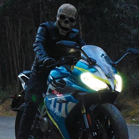 Persoon met schedelmasker op motorfiets 's nachts