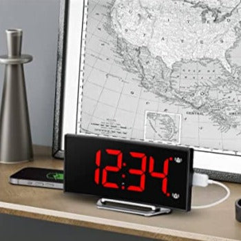 Digitale wekker met rode LED-tijd op een bureau.