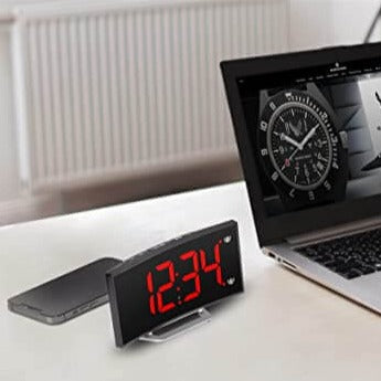 Digitale wekker met rode LED-tijd naast een laptop.