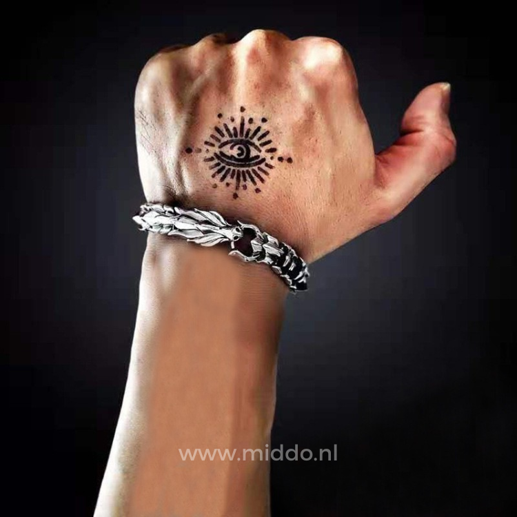 Hand met tatoeage draagt zilveren drakenarmband