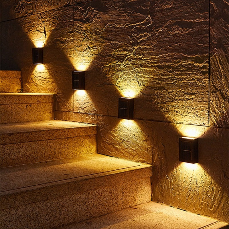 Buitenlampen verlichten stenen trap 's nachts met warme gloed.