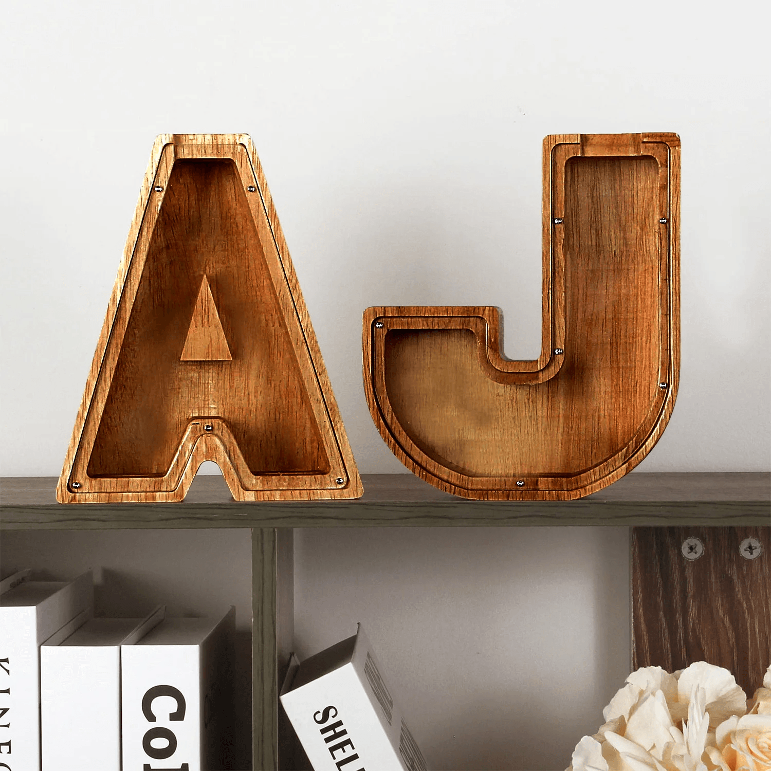 Houten spaarpot letters A en J op een plank als decoratie.