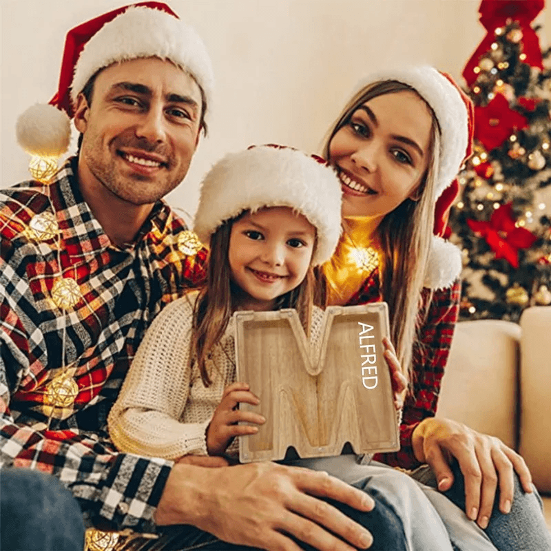 Familie met houten spaarpot letter M tijdens kerst.