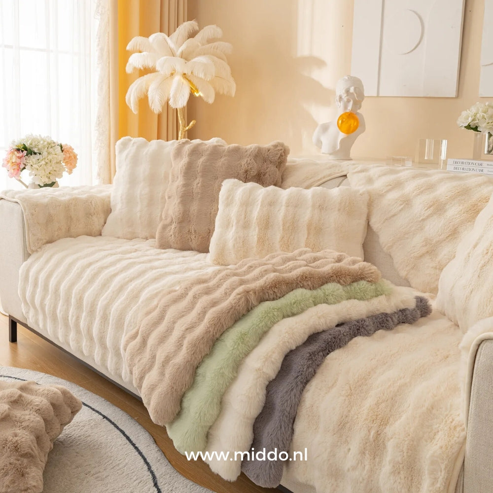 Beige bank met verschillende kleuren meubelhoezen, inclusief kussens en decoraties