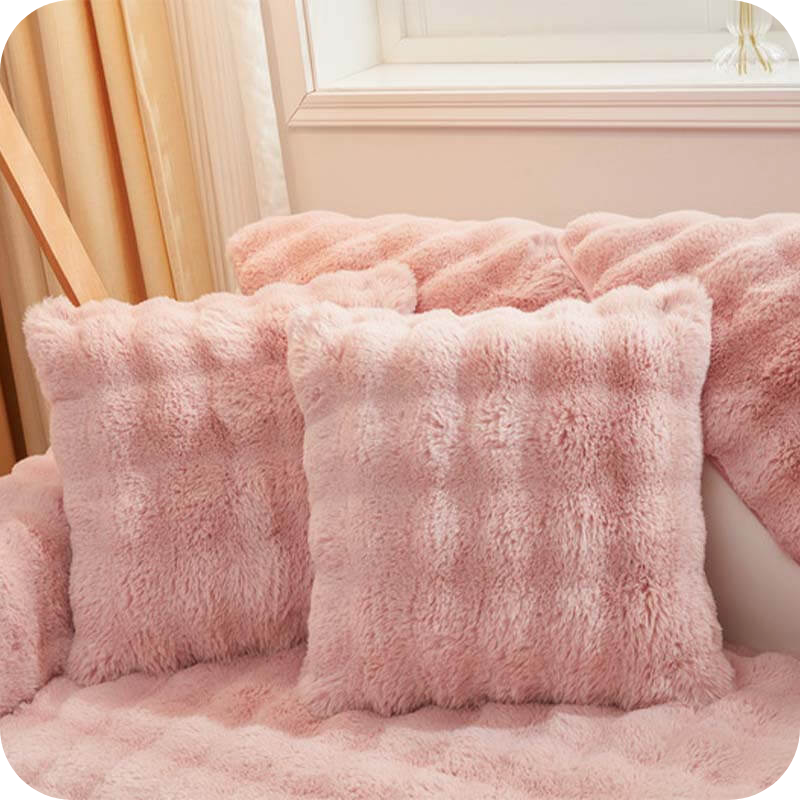 Roze pluche kussens en deken op een bank bij een raam